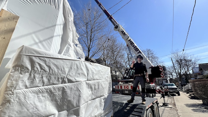 Jeremy Clark est debout sur un camion-remorque qui transporte des panneaux préfabriqués emballés.