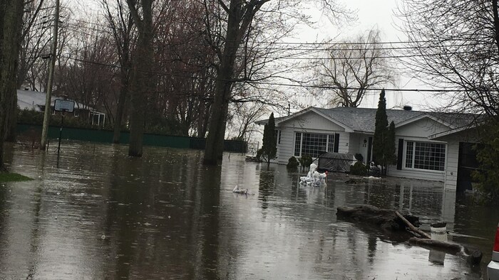 Une maison unifamiliale vue de l'extérieur avec tout son terrain inondé.
