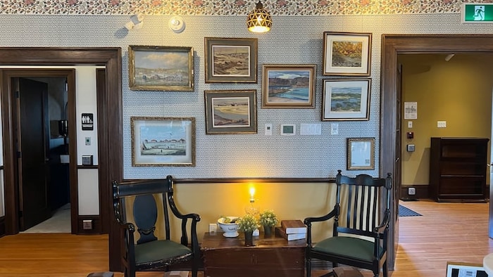 Deux chaises, une petite table et des tableaux d'époque.