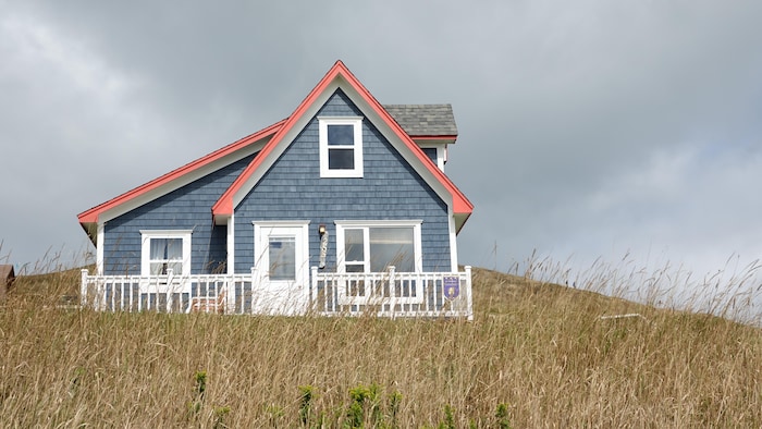 Une maison typique des Îles-de-la-Madeleine avec une pancarte d'établissement d'hébergement.