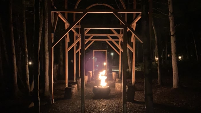 Une maison ouverte fait en bois avec un feu.