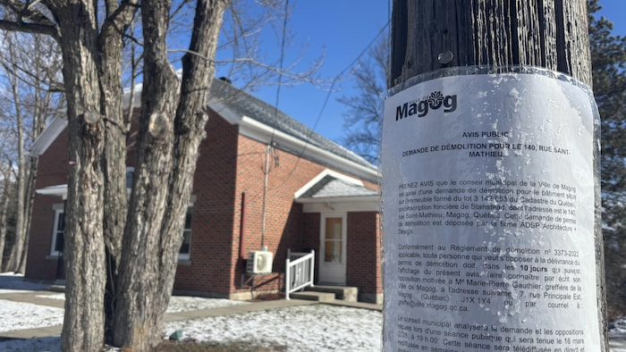 Un avis de démolition est affiché devant la résidence unifamiliale.