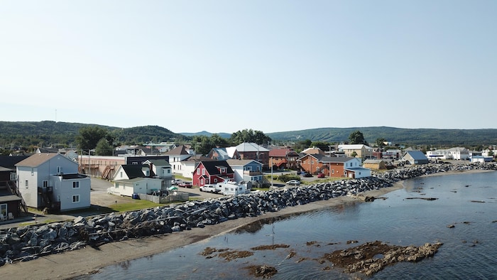 Vue sur une clôture de roches devant des maisons en bord de mer.