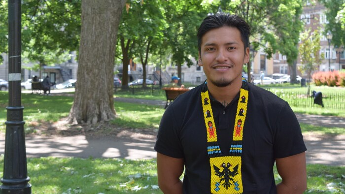 Un homme se tient debout dehors en portant une cravate traditionnelle.