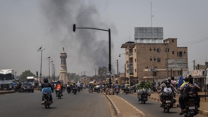 Une colonne de fumée noire s'élève au-dessus des bâtiments tandis que la circulation passe devant le monument de la Tour de l'Afrique à Bamako, le 26 avril 2026.