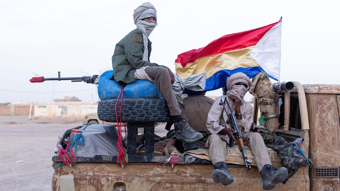 Des combattants armés à l'arrière d'une jeep.