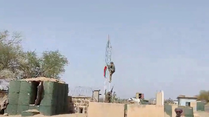 Un militant grimpe au sommet d'une tour surmontée d'un drapeau dans ce qui semble être une base militaire à Tessalit, au Mali, sur cette capture d'écran tirée d'une vidéo publiée sur les réseaux sociaux le 1er mai 2026.
