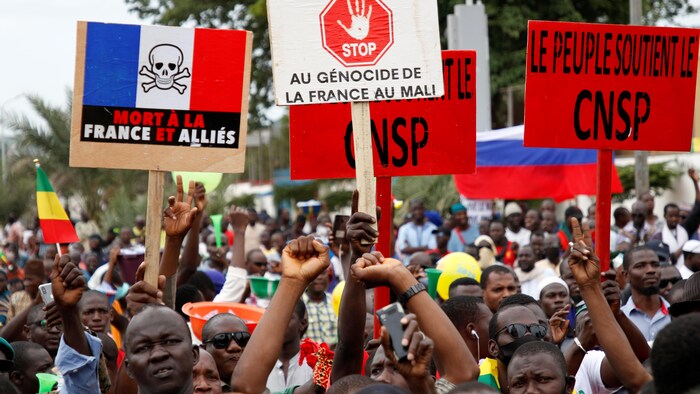 Des manifestants maliens brandissent des pancartes sur lesquelles sont écrits des slogans favorables aux militaires putschistes et hostiles à la France. 