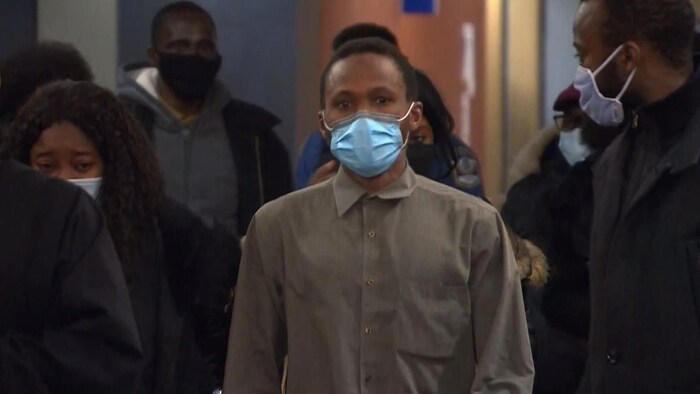Mamadi Camara, entouré de nombreuses personnes, marche vers la caméra.