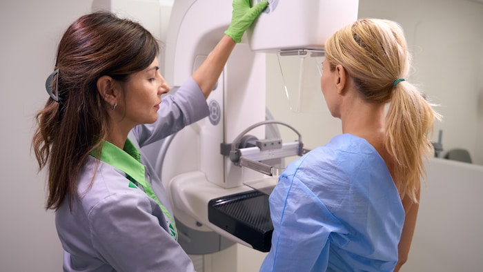 Une infirmière prépare une patiente pour une mammographie.