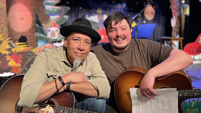 Deux artistes posent devant une scène.