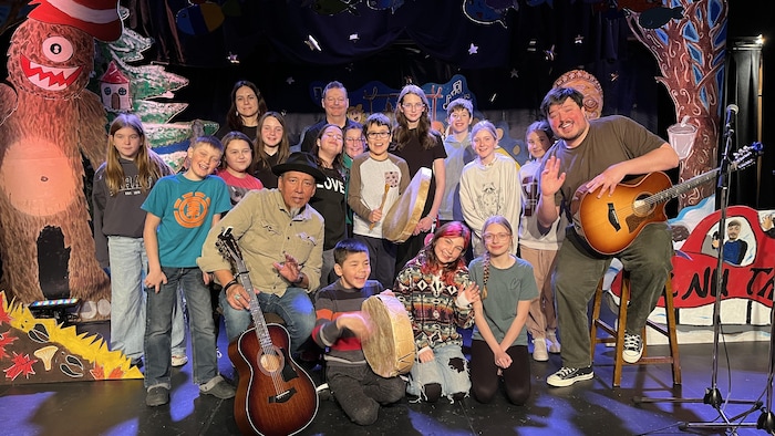 Des jeunes et des artistes posent sur une scène.