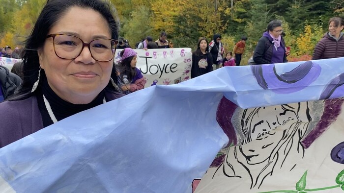 Une femme tient une bannière dans la cadre d'une marche pour commémorer le décès de Joyce Echaquan survenu deux ans plus tôt.