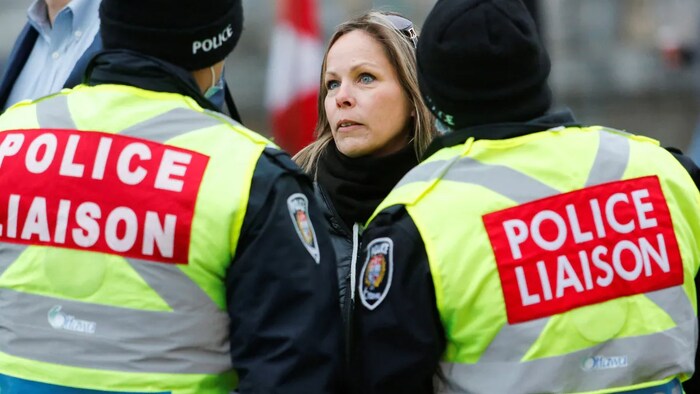 Une femme entourée de deux policiers.