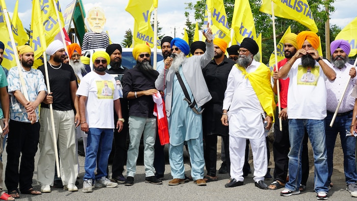 Des personnes sikhes autour d'un homme qui parle dans un microphone.