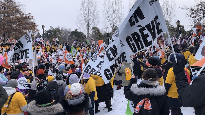 Des éducatrices et éducateurs en CPE brandissent des banderoles.