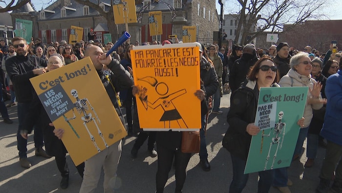 Des manifestants tiennent des pancartes.