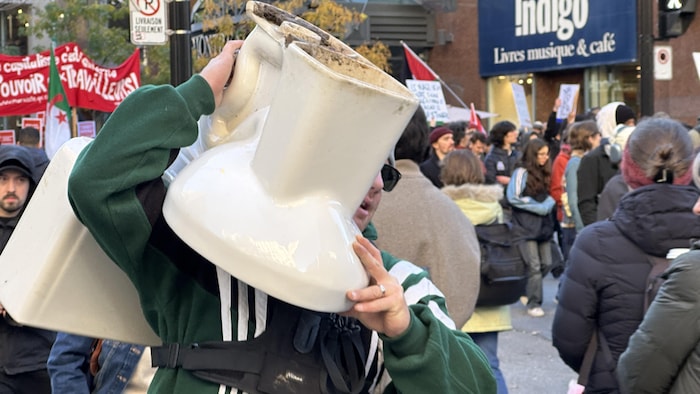 Un manifestant porte une toilette sur son épaule.