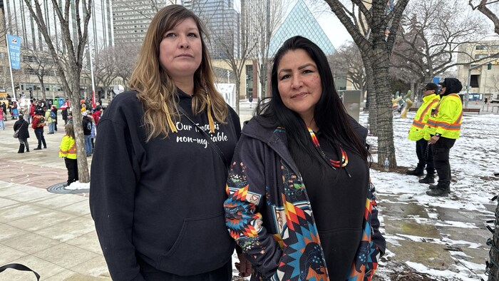 Deux femmes dans la neige avec des arbres en arrière-plan.