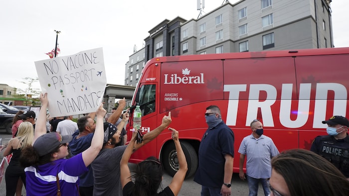 Una docena de personas hacen gestos vulgares ante el autobús de campaña del liberal Justin Trudeau.