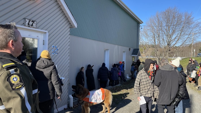 Des manifestants encerclent un bâtiment et tapent dessus avec leurs mains.