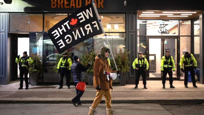 Un manifestant passe devant des policiers en file devant un bar.