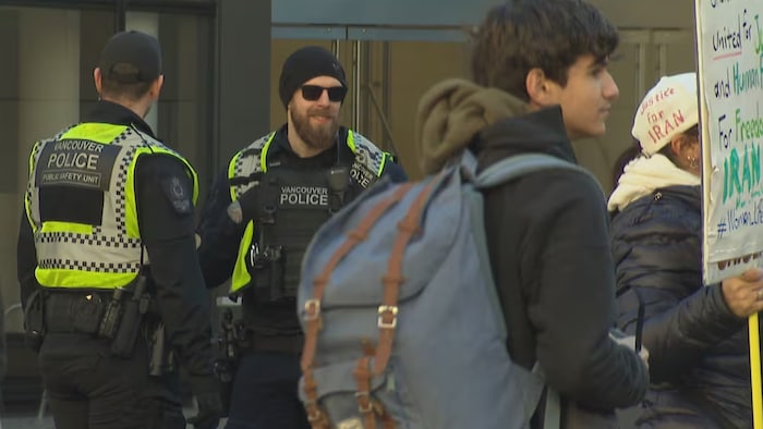 Deux policiers sont debout aux côtés de deux manifestants.