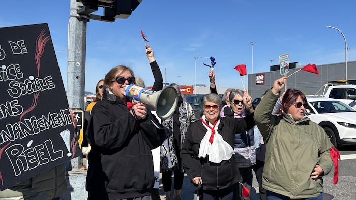 Un groupe de personnes manifeste en extérieur sous un ciel dégagé.