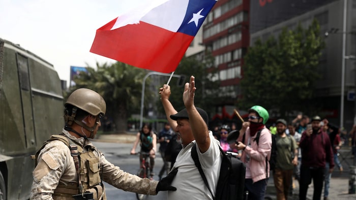 Un soldat stoppe un manifestant qui brandit un drapeau du Chili.