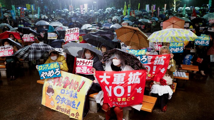 متظاهرون في طوكيو تحت الأمطار ويحملون لافتات.