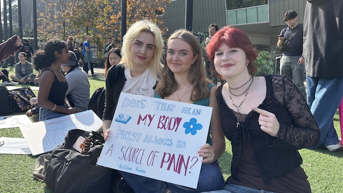 Trois jeunes manifestantes assises sur une pelouse.