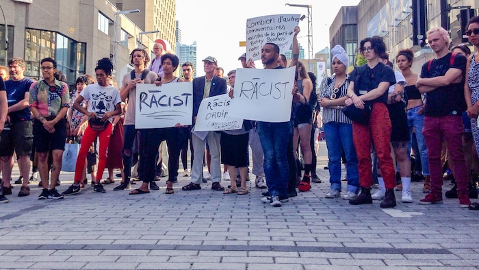 Des manifestants tiennent silencieusement des pancartes qui dénoncent le racisme derrière l'appropriation des chants d'esclaves par des artistes blancs, le 26 juin, durant une représentation du spectacle «SLAV».