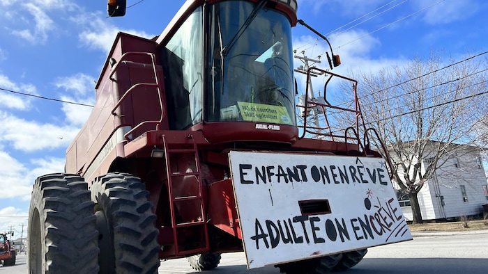 Un tracteur arborant une affiche qui dit Enfant on en rêve, adulte on en crève, lors de la manifestation du 8 mars 2024 à Rimouski.