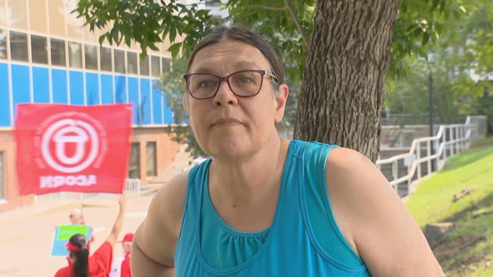 Une femme de face avec des manifestants et leurs drapeaux.