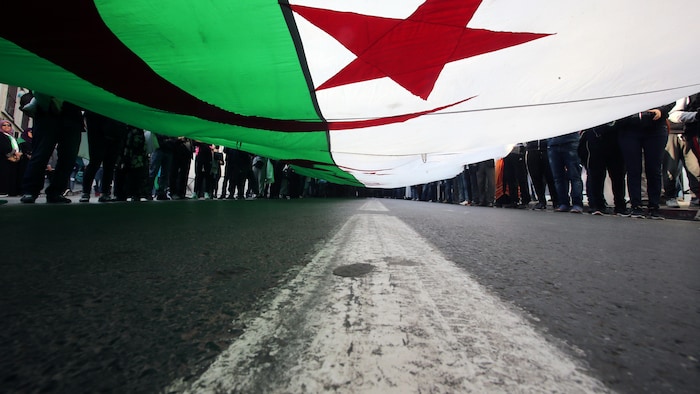 Un grand drapeau de l'Algérie est déployé.