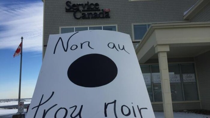 Affiche « Non au trou noir » devant le bâtiment de Service Canada de Cap-aux-Meules.