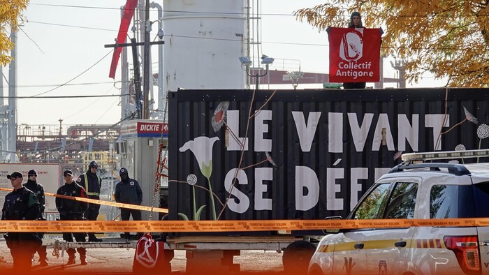 Des policiers et un manifestant perché sur un conteneur.
