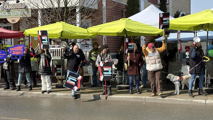 Des manifestants se font entendre à Warwick sur le trottoir avec des pancartes et des mégaphones. 