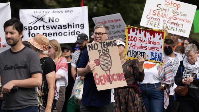 Des gens en rang avec des affiches durant une manifestation.