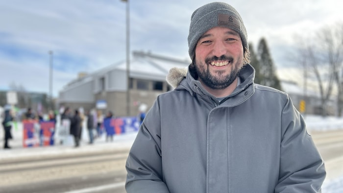 Un homme sourit dehors l'hiver.
