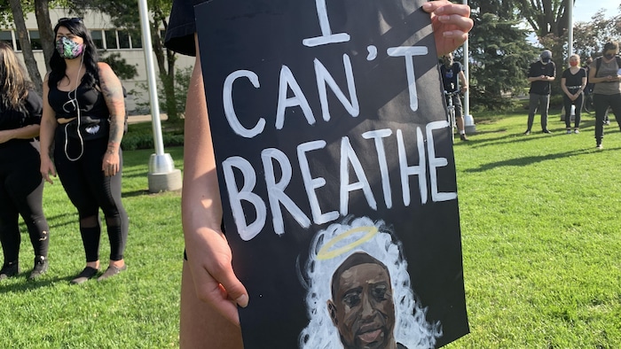 Une manifestante tient une affiche de George Floyd sur laquelle il est écrit : « Je ne peux plus respirer. »