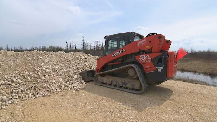 Une machine à chenilles à côté d'un barrage de gravier.