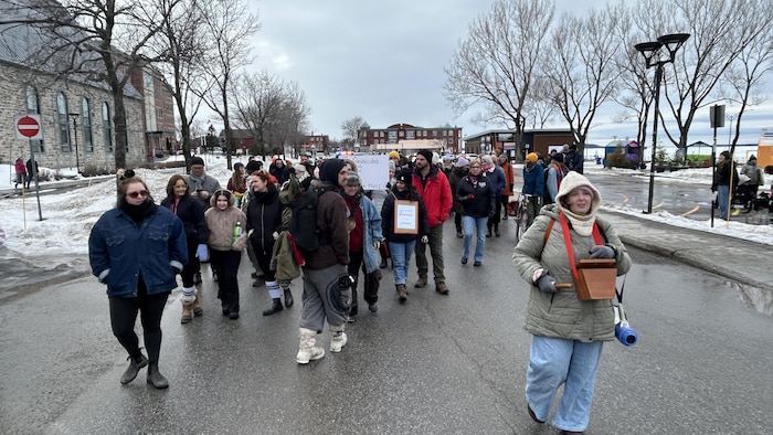 Une femme tape dans une percussion à l'avant d'un petit cortège de manifestants, lors de la Journée internationales des droits des femmes.