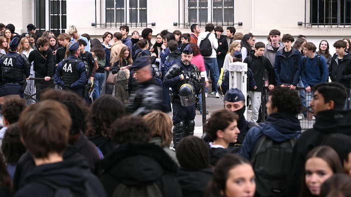 Des agents du Corps républicain de sécurité (CRS) se tiennent aux côtés d'élèves qui bloquent l'entrée du lycée Montaigne à Paris, le 9 octobre 2026.