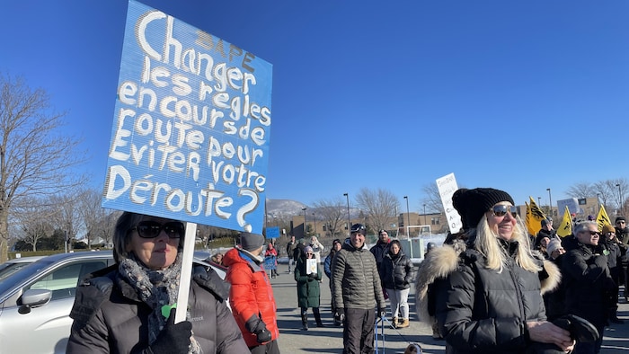 Des manifestants sont réunis à McMasterville, le 4 février 2024, dans le cadre d'une marche funèbre, avec notamment une personne avec une pancarte « BAPE - Changer les règles en cours de route pour éviter notre déroute? ».
