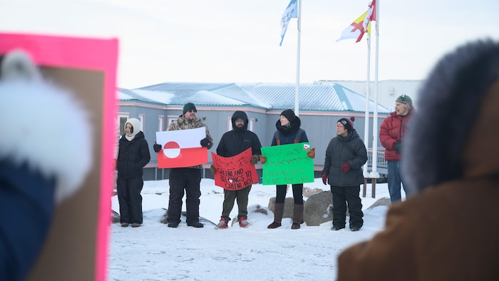 Des personnes alignées tiennent des pancartes. 