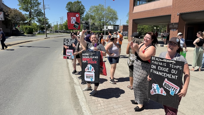 Un groupe de personnes manifestent dans la rue, pancartes en main.