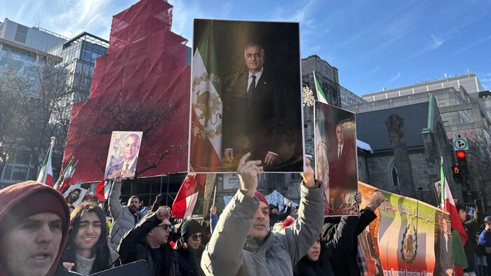 Un manifestant dans la foule brandit une photo de Reza Pahlavi.
