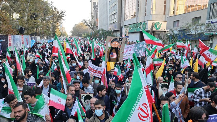 Des Iraniens agitent des drapeaux nationaux de leur pays alors qu'ils participent à un rassemblement dans la capitale Téhéran, le 4 novembre 2022.