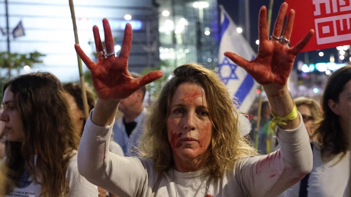 Une manifestante avec du faux sang sur ses mains et sur son visage. 
